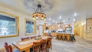 A spacious kitchen with wooden cabinets, a central island, and a dining area with a wooden table and chairs. - Covered Patio, Creek & Mtn Views: Afton Nature Hub (Afton)