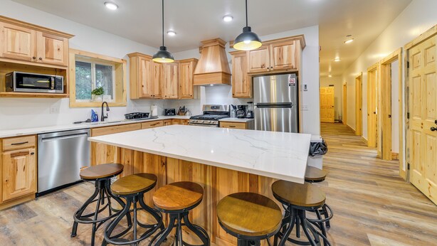 A modern kitchen with wooden cabinets, stainless steel appliances, and a central island with stools. - Covered Patio, Creek & Mtn Views: Afton Nature Hub (Afton)