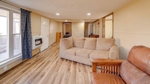 A living room with a beige sofa, a brown leather chair, a wooden coffee table, and a large window with curtains. - 4 Mi to Gauley River Rapids! Outdoor Adventure Hub (Summersville)