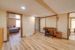 Una habitación con piso de madera, una cama, un escritorio con silla y una mesita.