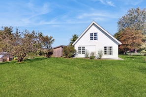 A white house with a gabled roof, a front porch, and a well-maintained lawn.