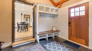 A wooden bench, a coat rack, and a door in a room with a sloped ceiling and a patterned rug. - Hike, Bike, & Explore: Vermont Family Farmhouse! (New Haven)