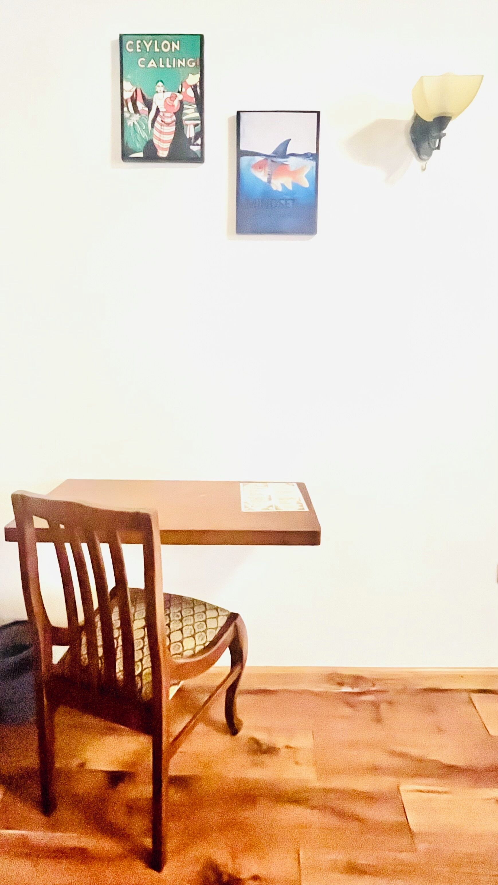 Ein Zimmer mit einem Holztisch, einem Stuhl und zwei gerahmten Bildern an der Wand.