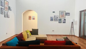 Una sala de estar con un sofá, una mesita de centro y una lámpara de pie. Hay cuadros enmarcados en las paredes.