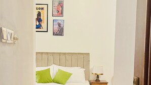 Un dormitorio con cama, mesita de noche, ventilador de techo y decoración en la pared.