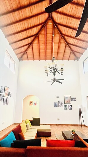 A living room with a ceiling fan, a chandelier, and a sofa with cushions. - Mara Villa Katunayake - 5 Mins to Colombo Airport (Seeduwa - Katunayake)