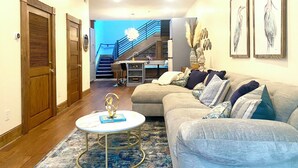 A spacious living room with a large couch, a small coffee table, and a staircase leading to an upper level.