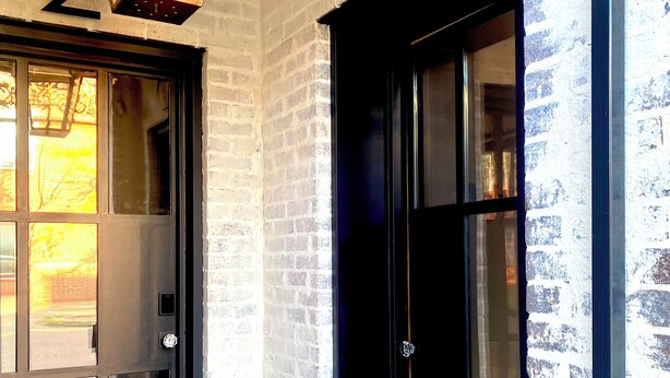 A building entrance with numbered doors, a doormat, and a hanging light fixture.