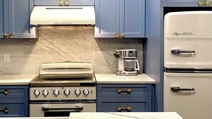 A kitchen with blue cabinets, a white stove, and a white refrigerator.