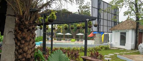 Un espacio al aire libre techado con piscina, bancos y macetas colgantes.