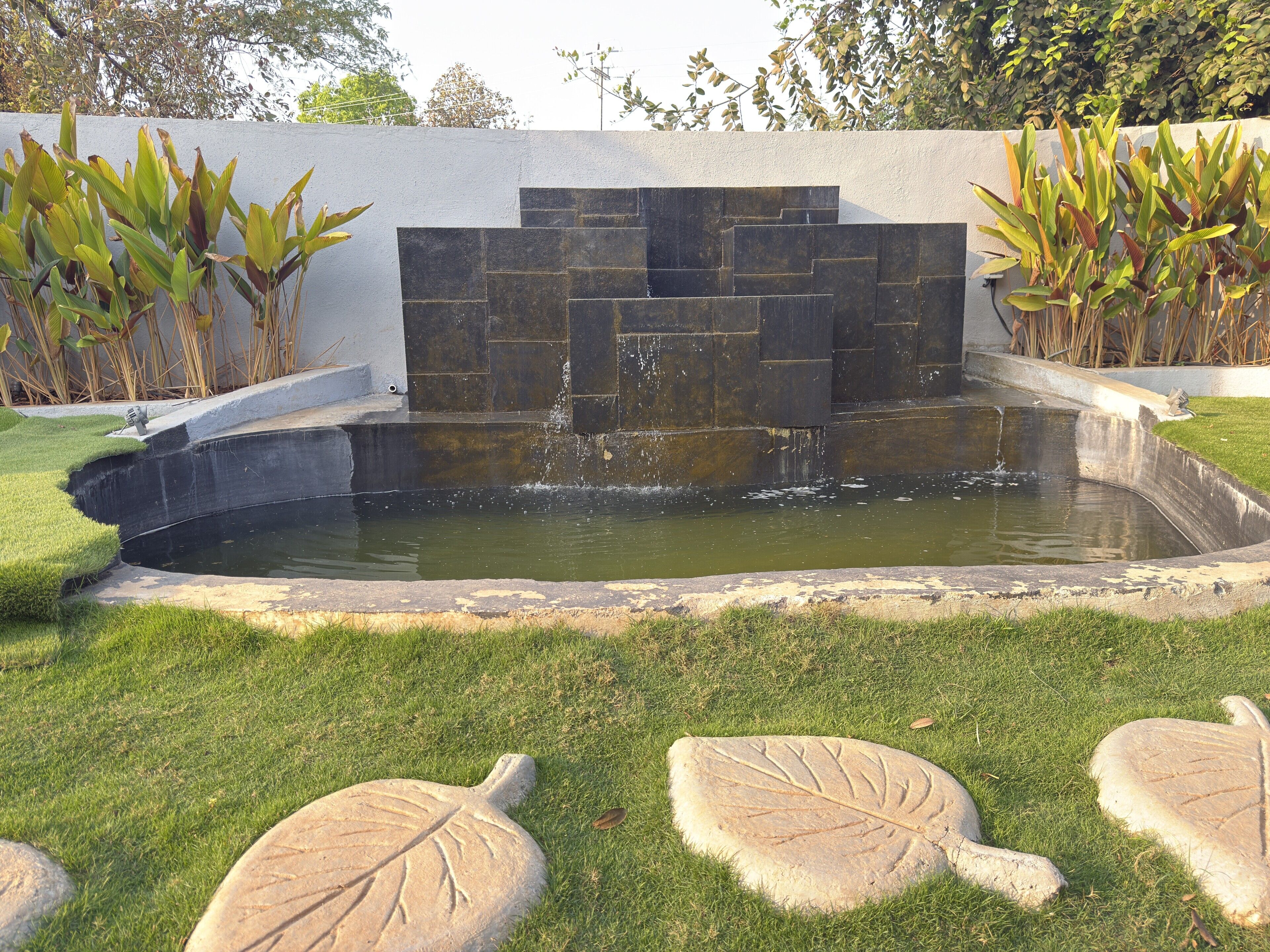 A garden with a pond, stone steps, and leaf-shaped stepping stones.