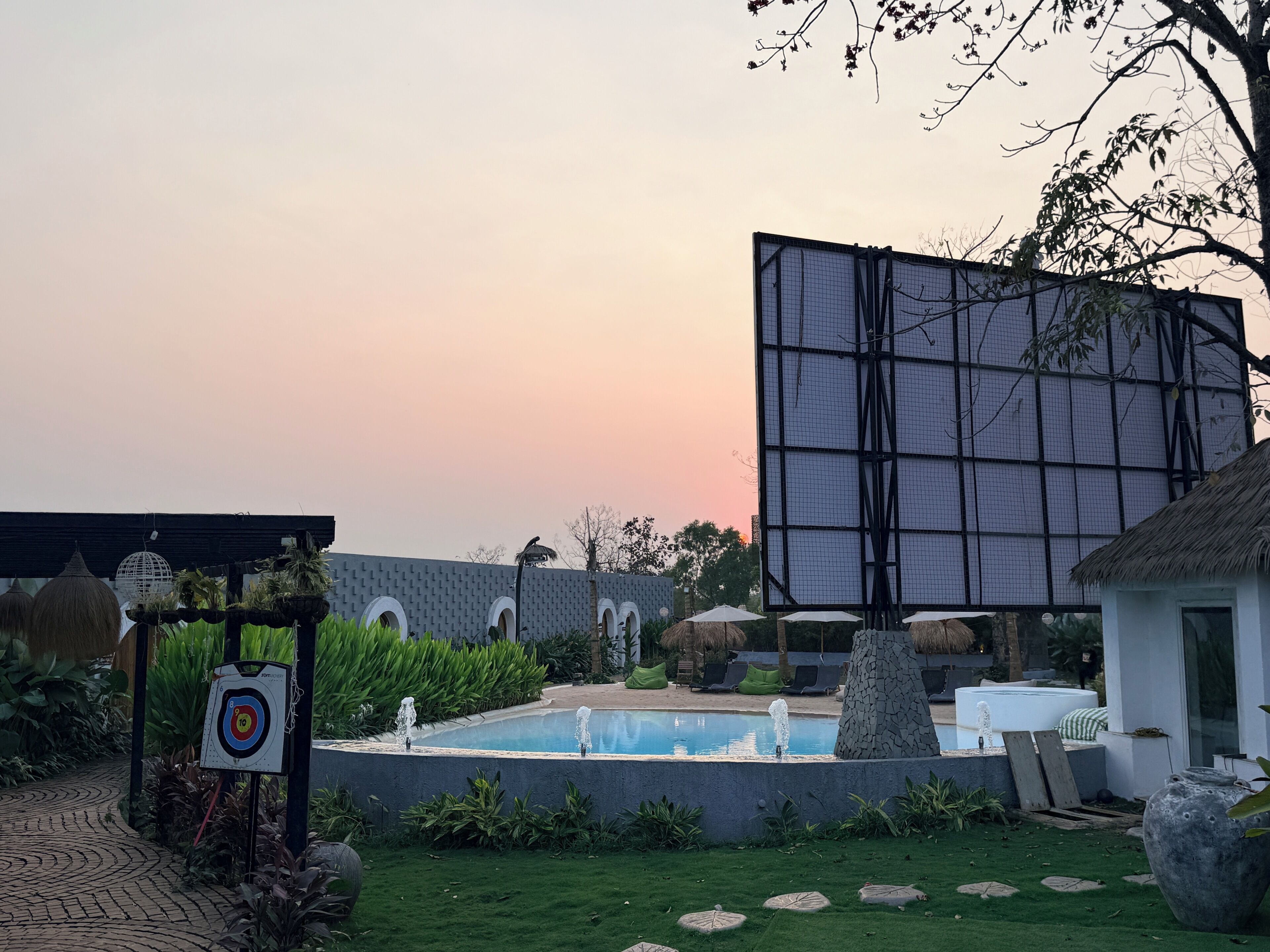 A pool area with a target, a large screen, and a thatched-roof structure.