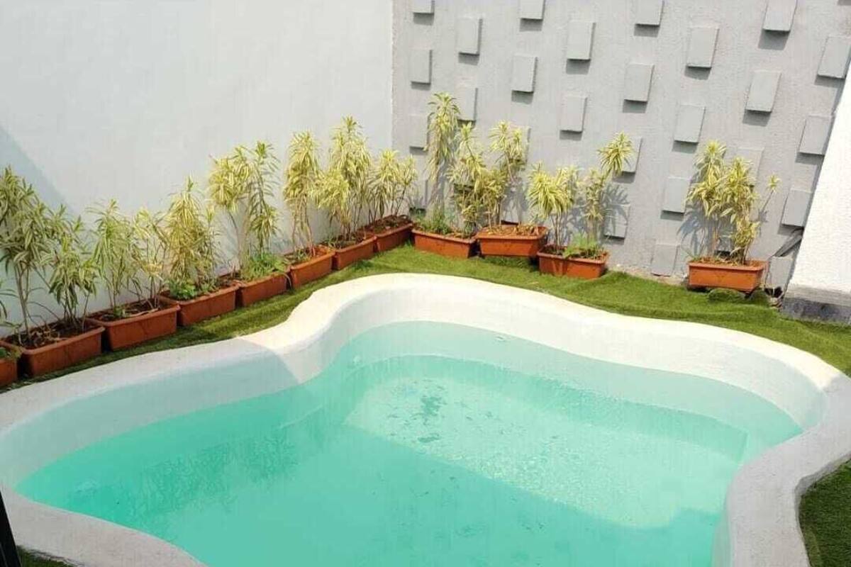 A small, irregularly shaped pool with a light blue color, surrounded by a white border and a patch of artificial grass.