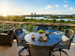 Un balcon avec une table ronde, deux chaises, un pot de fleurs et une cafetière.