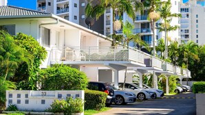A modern residential building with multiple balconies, parked cars, and lush greenery. - The Wharfside Oasis by the Waves (Surfers Paradise)