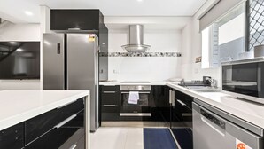 A modern kitchen with a stainless steel refrigerator, a built-in oven, a microwave, and a gas stove. - The Wharfside Oasis by the Waves (Surfers Paradise)