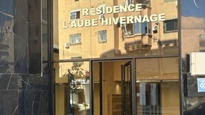 Una entrada de edificio con puerta de vidrio y el letrero 'RESIDENCE L'AUBE HIVERNAGE'.