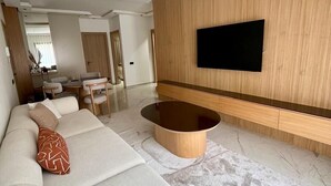 Una sala de estar moderna con un sofá, una mesita de centro y un televisor de pantalla plana montado en una pared de madera.