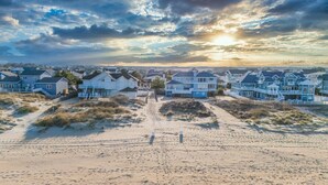 A beachfront property with multiple houses, a sandy beach, and a clear sky.