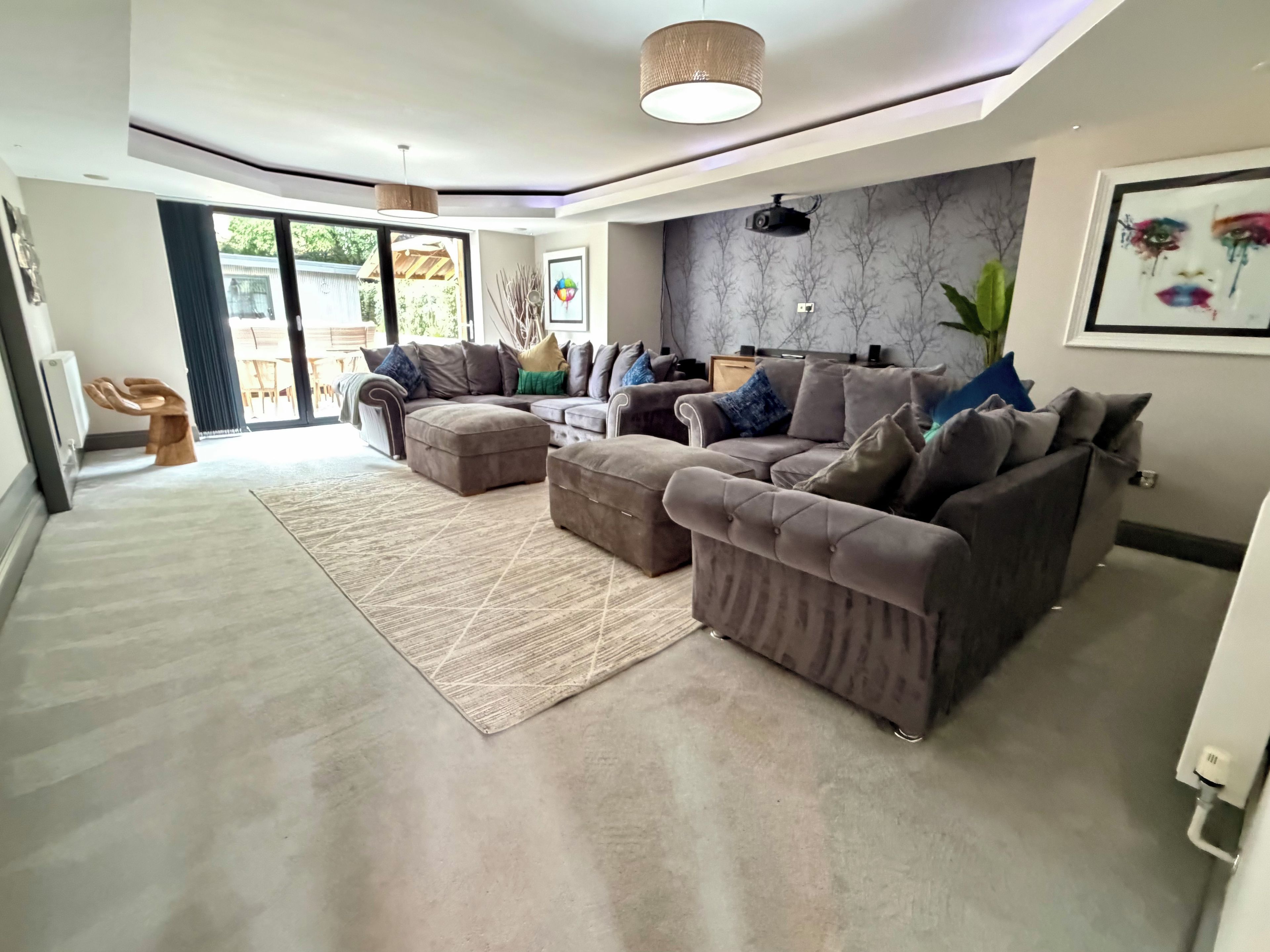 A modern living room with a sectional sofa, ottoman, and a large rug.