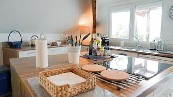 Una cocina con encimera de madera, estufa de vidrio y ventana con vistas.