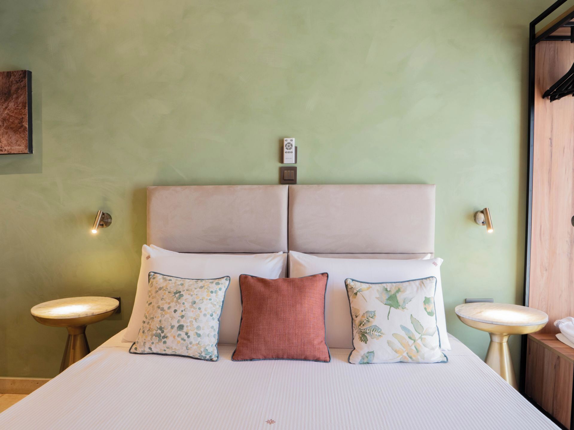 Una habitación de hotel con una cama grande, dos mesitas de noche y una lámpara fijada a la pared.