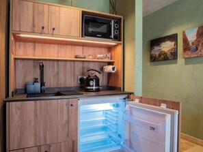 A compact kitchen with a built-in microwave, kettle, and a mini-fridge.