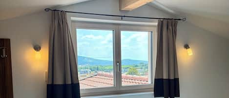 A room with a window, curtains, and a wooden beam.