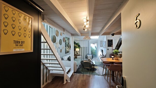 Een modern interieur met een trap, een eethoek en een muur met een lichtbubbelsign.