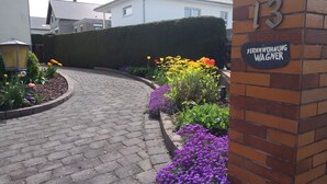 Un sendero pavimentado que conduce a la entrada de un edificio, con un muro de ladrillo y un letrero que dice 'Feriendorf Wagner'.