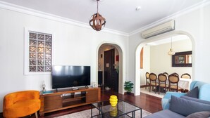 A modern living room with a flat-screen TV, orange armchair, and a glass coffee table. - Cozy 3BR Apartment in Şişli Close to Cevahir Mall (İstanbul)