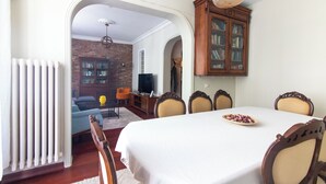 A dining area with a white table, wooden chairs, and a bookshelf. - Cozy 3BR Apartment in Şişli Close to Cevahir Mall (İstanbul)