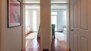 A hallway with wooden flooring leading to two bedrooms with white beds and a large window. - Cozy 3BR Apartment in Şişli Close to Cevahir Mall (İstanbul)