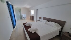 Une chambre d’hôtel avec un lit, une table de chevet, une lampe, une commode et une salle de bain visible au fond.