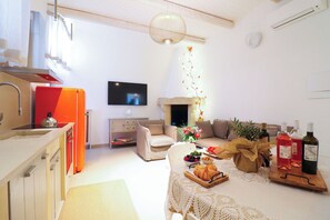 Ein Wohnzimmer mit einer Couch, einem Flachbildfernseher, einem Kamin und einem Tisch mit Speisen und Getränken.