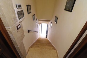 Un escalier étroit doté d’une rampe, menant à une pièce lumineuse située à l’étage.