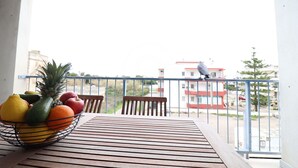 Een balkon met een tafel, stoelen en een fruitschaal.
