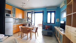 Een compacte hotelkamer met een kitchenette, een eethoek en een zithoek met een televisie.
