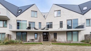 Un edificio residenziale moderno a più piani, con facciata simmetrica, ampie finestre e un ingresso centrale.