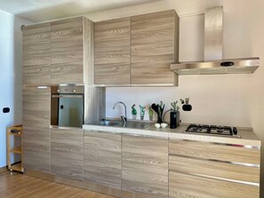 A modern kitchen with built-in appliances, a stainless steel range hood, and a minimalist design. - Lovely apartment for 4 people with WIFI, TV, patio, pets allowed and panoramic view (Aurogna)