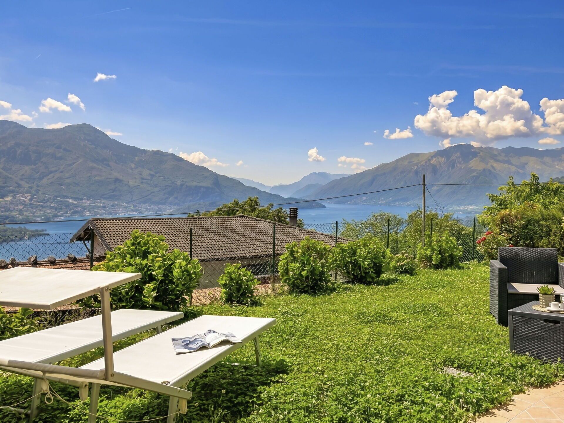 A terrace with a table and chairs, a small building, and a mountainous backdrop.
