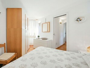 A bedroom with a bed, a wooden wardrobe, a bedside table with a plant, and a mirror on the wall. - Nice apartment for 4 people with pool, A/C and pets allowed (Arzachena)