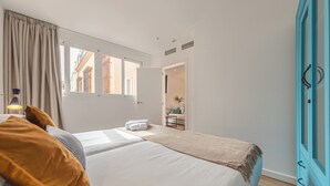 Una camera da letto con un letto, un comodino, una finestra e una porta che dà su un'altra stanza.