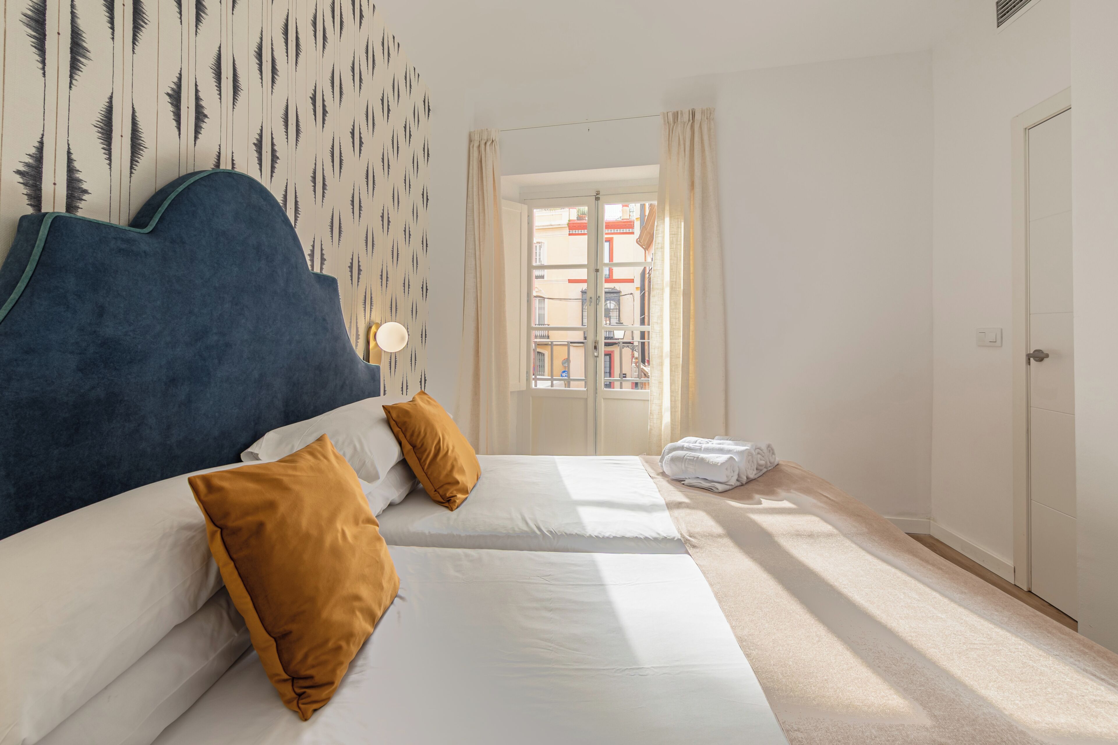 Een hotelkamer met twee bedden, uitzicht op de straat en een deur.