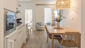 Una cucina moderna con forno integrato, macchina per il caffè e zona pranzo con tavolo in legno e sedie in vimini.