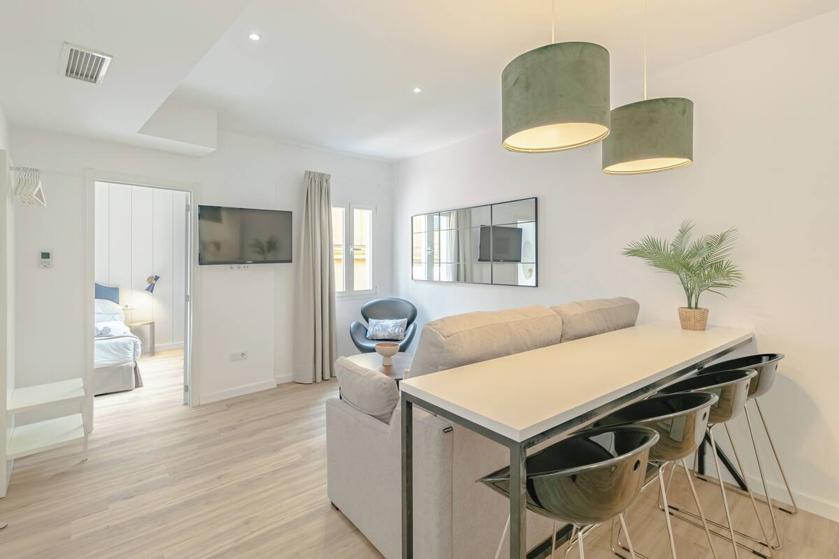 Una cocina moderna con comedor, televisor y una planta.