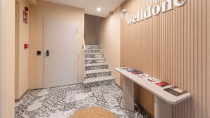 Un'area reception con un cartello 'weldone', una scala a motivi decorativi e una scrivania per gli ospiti con brochure.