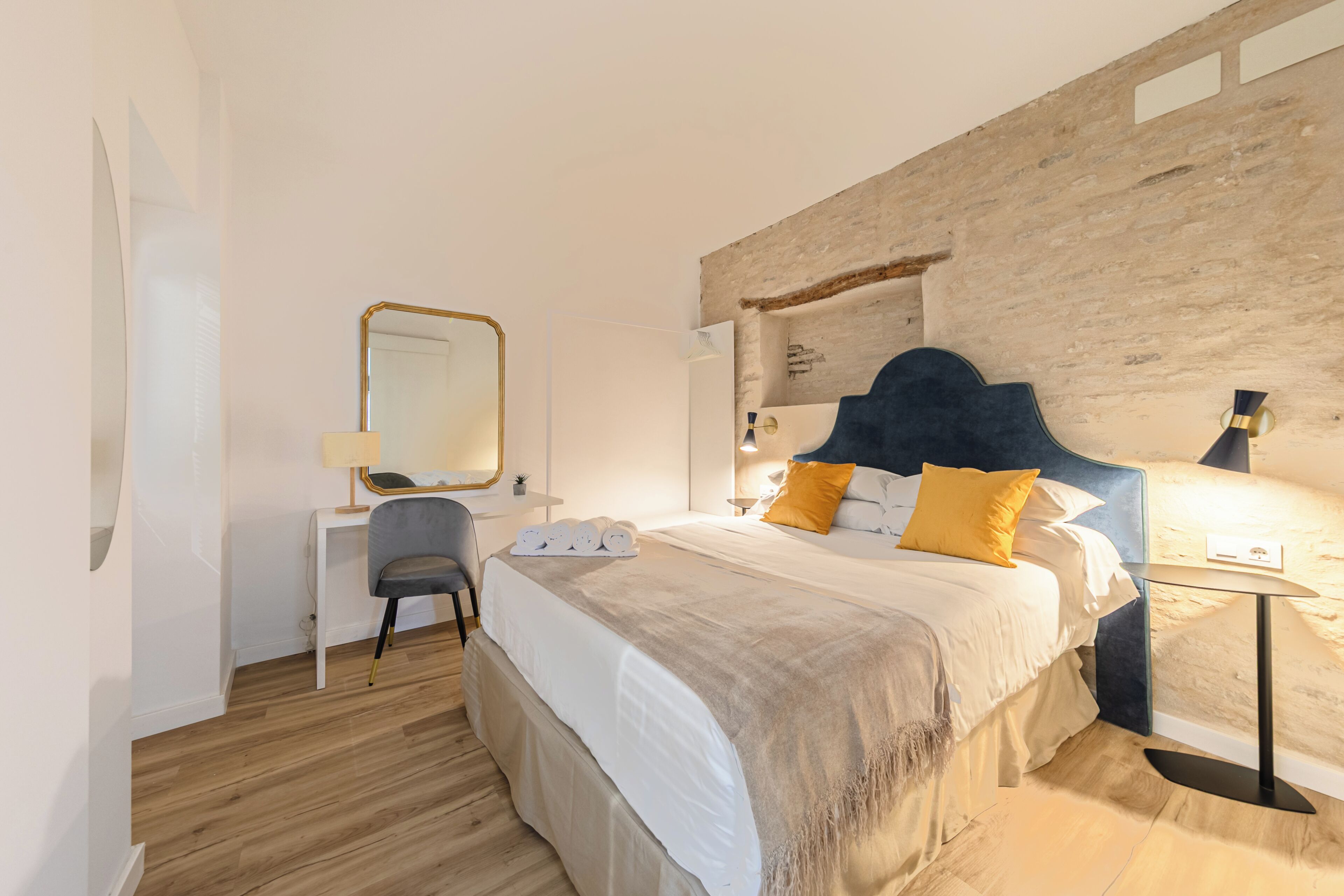 Une chambre à coucher avec un lit, un bureau, une chaise, un miroir et une lampe.