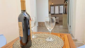 Une bouteille de vin posée sur un tapis tissé, avec deux verres à vin vides sur une table en bois.