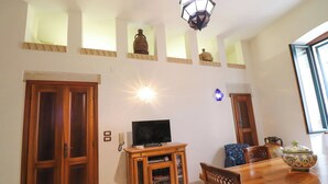 A dining area with a wooden table and chairs, a television on a wooden cabinet, and decorative vases on shelves. - Beautiful private villa for 4 people with A/C, WIFI, TV and panoramic view (Otranto)